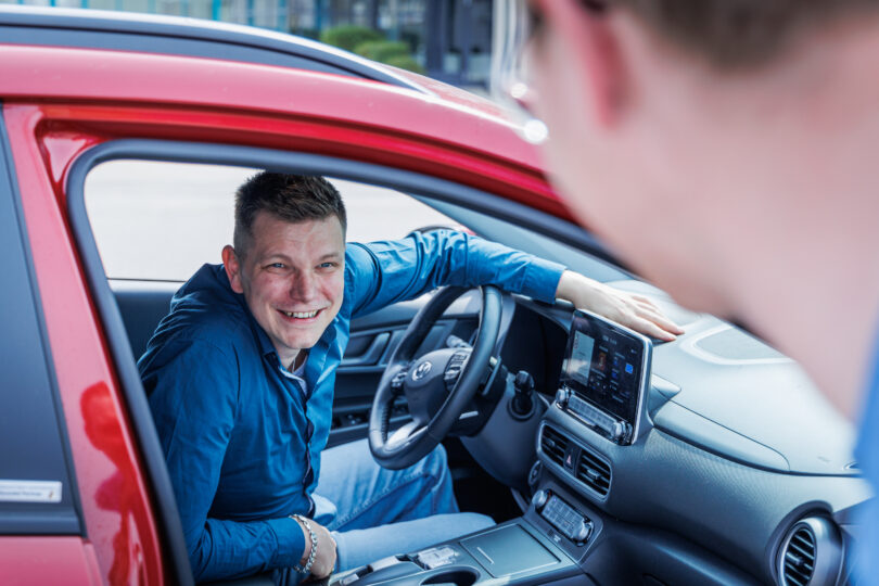 Mitfahrbörse, eine Person hinter dem Lenkrad, eine einsteigende Person